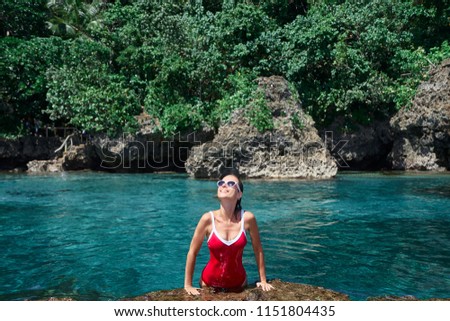 Summer vacation. Beautiful young woman in red swimsuit at sea natural pool.