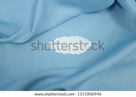 Blank white paper on blue soft fabric background. Copy space