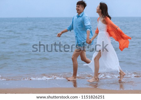 Young asian couple playing on beach.