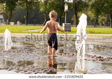 Baby boy playing in fountain. Concept of happiness and carefree childhood.