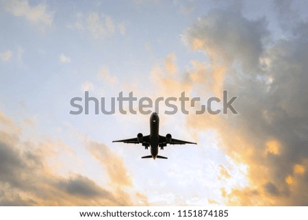Silhouette of flying passenger plane. airplane landing during a sunset sky background. Jet civil aircraft with two engines. Orange clouds.
