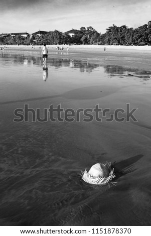 Vertical picture of a beach with a hat in the water