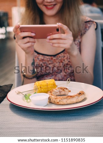 Young pretty girl in cafe taking photo of food.