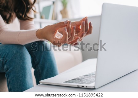 cropped shot of woman showing mudra sign and doing exercise for fingers while using laptop