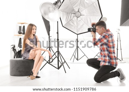 Young woman posing for professional photographer on white background in studio