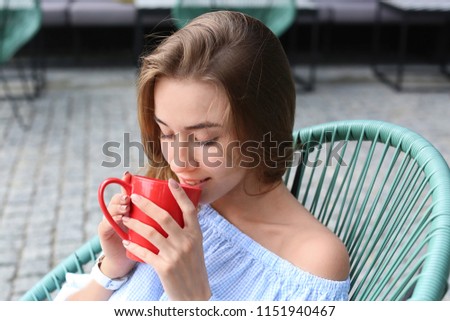 Beautiful young woman drinking sweet cocoa in cafe outdoors