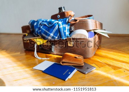 overloaded suitcase with clothes. travel concept. bag with garment. biometric passport in front