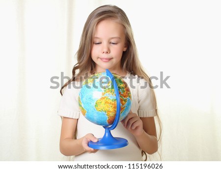 Little blond girl holding and looking on globe