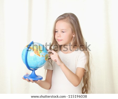 Little blond girl picking a globe by finger