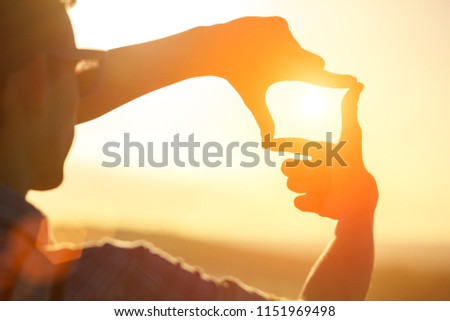 Human hands making a frame sign over sunset sky