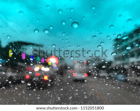 Defocused image, Water drops on car windshield, traffic in the city on a rainy day at evening. Colorful bokeh, dark and blurred background.