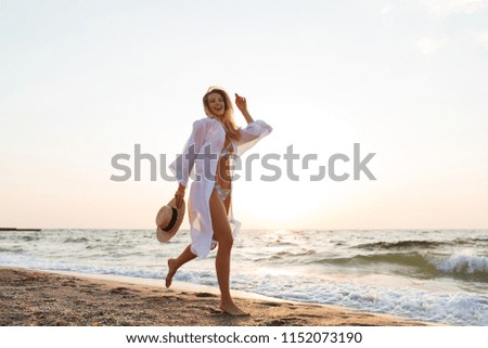 Picture of pretty young woman with hat walking outdoors at the beach.