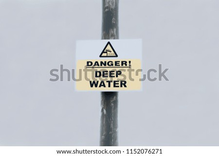 Danger deep water sign on post against sky background at sea harbour