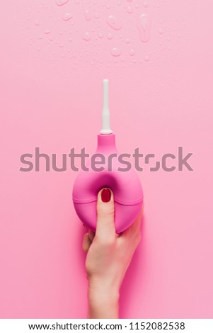 cropped shot of woman holding douche on pink Royalty-Free Stock Photo #1152082538