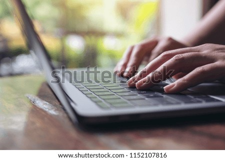Closeup image of hands using and typing on laptop keyboard on wooden table