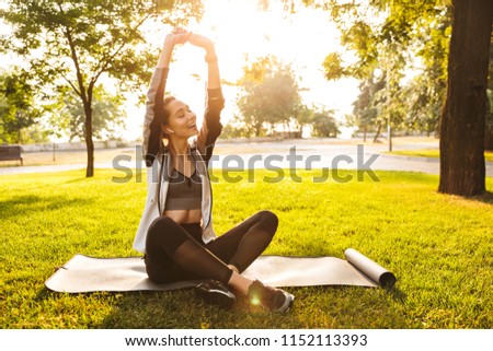 Picture of beautiful cute fitness sports woman in park outdoors listening music with earphones.