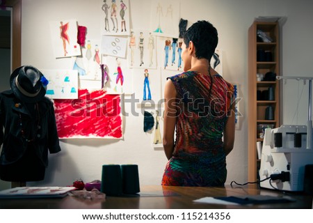 Young people and small business, hispanic woman at work as fashion designer and tailor, looking at sketches of new collection in atelier