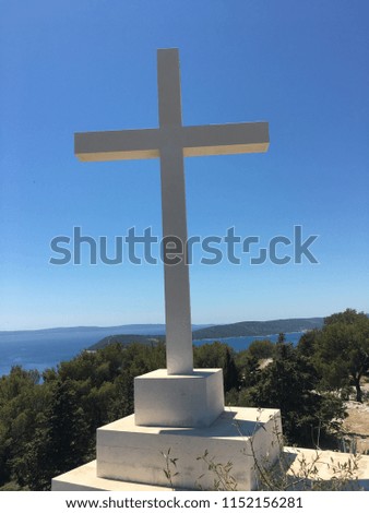 White Cross on a hill with forest and ocean background