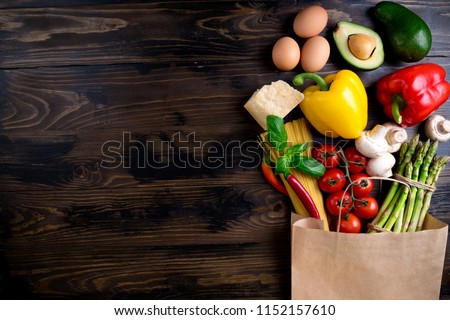 Healthy food background. Healthy food in paper bag vegetables, pasta, eggs, cheese and mushrooms on dark. Ingredients for cooking pasta. Shopping food supermarket concept. Top view Royalty-Free Stock Photo #1152157610