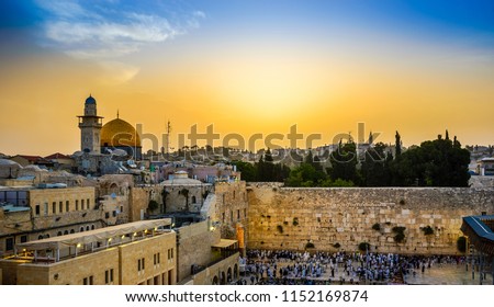 Jewish people gather for Shacharit sunrise prayer at the Western/Wailing Wall, the holiest place in Judaism, with the muslim Dome of the Rock, the Temple Mount and Mount of Olives in the background Royalty-Free Stock Photo #1152169874