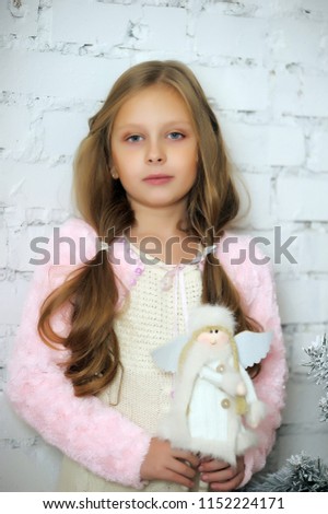 portrait of a young girl with a toy angel in her hands