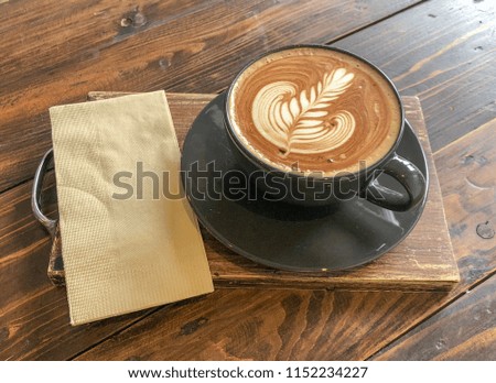 Hot Mocha Latte Coffee decorated with latte art. In black coffee mug Put on wooden board Put on wooden board. Available space for adding text.