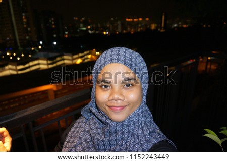 A young cute hijab girl selfie with background city at night.