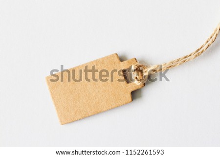 Blank brown cardboard price tag, sale tag, gift tag, address label, luggage label on white background. Mock up, copy space for text, top view