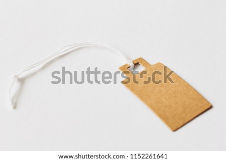 Blank brown cardboard price tag, sale tag, gift tag, address label, luggage label on white background. Mock up, copy space for text, side view