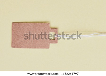 Blank brown cardboard price tag, sale tag, gift tag, address label, luggage label on yellow background. Mock up, copy space for text, top view