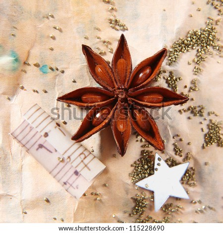 Grunge Christmas still life with star anise spice, a traditional star and music notes on stained, aged, crumpled vintage paper with scattered seeds