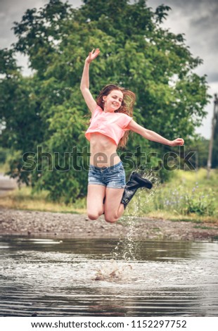 happy girl jumping in a puddle in the rain