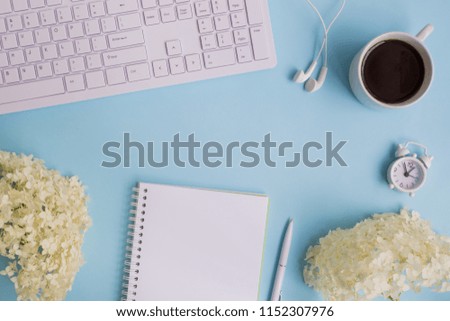 Blogger or freelancer workspace with notebook and white flower hydrangea on blue background