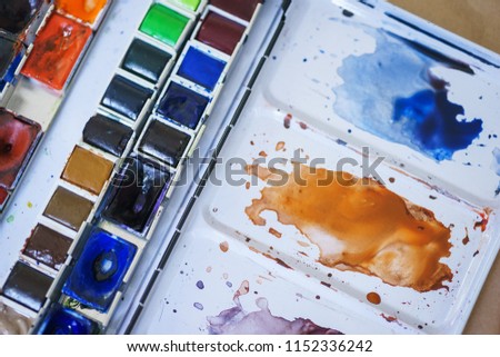 Spots of watercolor paint on a plastic palette. Drawing and art. Abstract background. Soft focus and beautiful bokeh. Stains of paint on special plastic containers. 