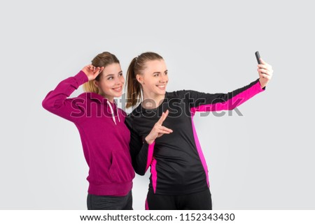 Two young attractive woman wearing spots suit  photograph themselves on phone