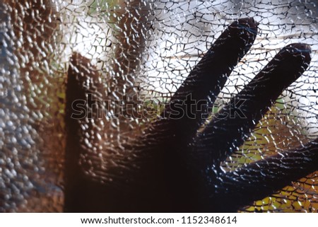 silhouette of a hand on a broken glass