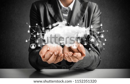 Businessman in suit keeping cloud with network connections in hands with gray wall on background.