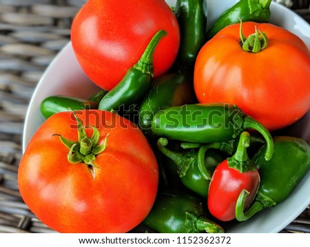 diagonal angle of tomatoes in a bowl of jalapenos