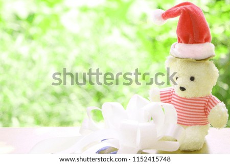 One teddy bear wear red Christmas cap with white bow on blur green bokeh background have copy space