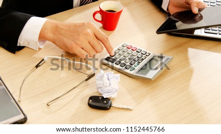 Close up to business man hand touch calculatorand using tablet on wood table desk backgrounds