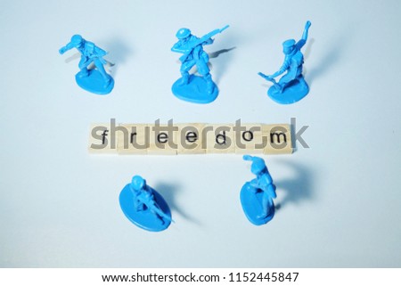A flatlay picture of miniature army and word tiles creating freedom. Freedom is a precious thing a people need to take care.