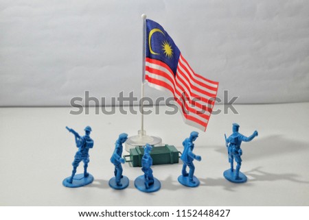 A picture of the miniature army facing the Malaysia flag. It is showing that the flag of the nation must be respect by all people.