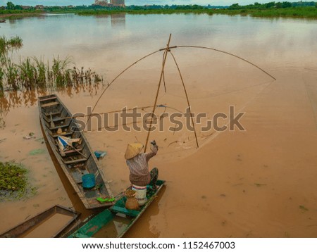 Fisherman in the Mekong with ancient fishing tools