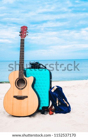 a guitar a baggage and a bag put on the beach on holiday.