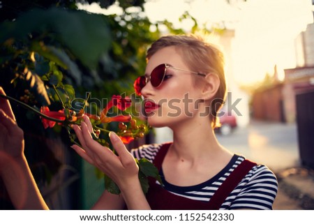 woman in glasses on the street sniffing flowers                               