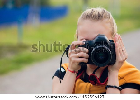 female photographer in the field with camera taking pictures