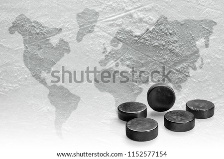 Fragment of the ice arena with the image of the world map and hockey pucks