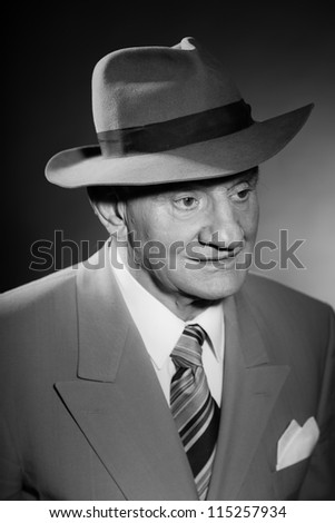Senior glamour vintage man wearing suit and tie and hat. Black and white studio shot. Gangster look. Isolated.