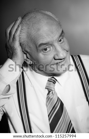 Senior glamour vintage man wearing white shirt, tie and striped braces. Black and white studio shot. Gangster look. Isolated.