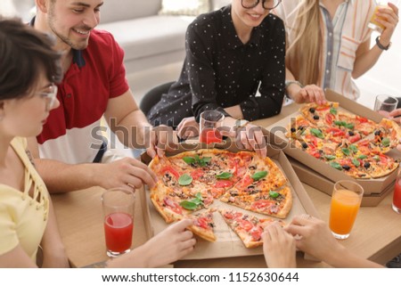 Young people eating delicious pizzas at table, closeup